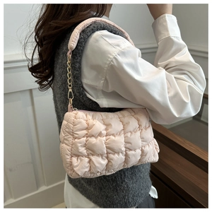 Detail of light pink quilted puff shoulder bag with golden chain strap on a model