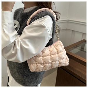 Detail of pink quilted cloud bag with gold chain strap worn as a trendy shoulder bag