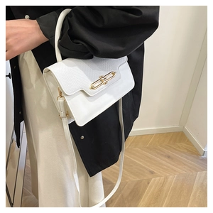Detailed view of white crossbody bag with lizard pattern texture and gold buckle