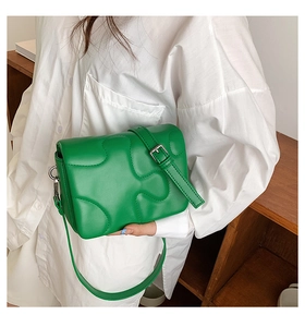 Macro detail of bright green crossbody bag with unique puzzle textured embossed pattern