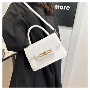 Detail of white textured handbag featuring gold metal buckle and contrast stitching
