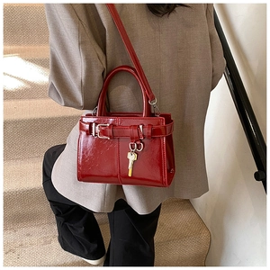 Vue détaillée du sac à main rouge en cuir verni avec pendentif clé dorée sur modèle