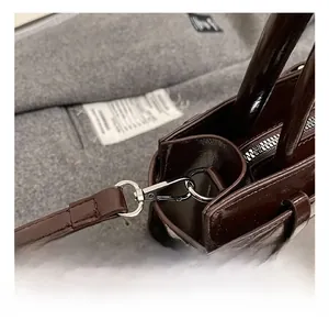Détail du sac en cuir marron foncé brillant avec fermoir mousqueton en métal argenté