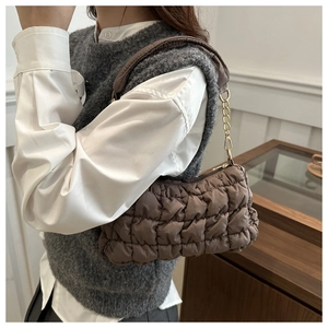 Detail of tan ruched cloud bag featuring quilted fabric and gold metal chain strap