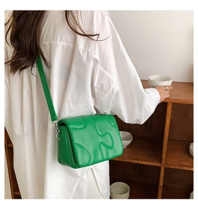 Detail of green quilted crossbody bag with unique wave texture and adjustable strap