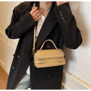 Detail of khaki lychee grain leather handbag with gold hardware and white stitching