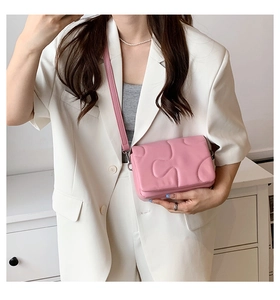 Pink quilted crossbody bag with unique puzzle pattern and adjustable leather strap