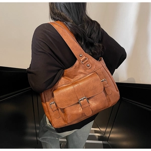 Detail view of vintage brown soft leather tote bag with metal buckle and multi-pocket design