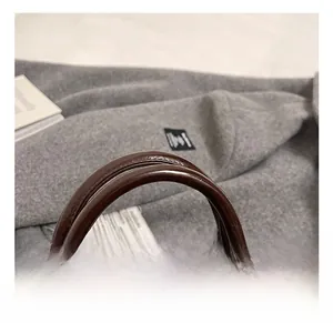 Détail de la poignée en cuir marron foncé et de la boucle en métal sur les sacs