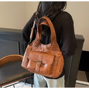 Back view of a woman carrying a brown vintage faux leather handbag with buckle details