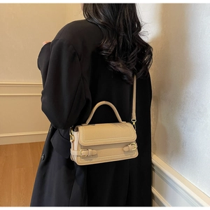Detail of beige lychee pattern bag with decorative stitching and gold metal hardware