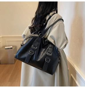 Vue arrière d'un mannequin portant un grand sac cabas noir avec des boucles en métal