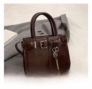 Détail du sac à main en cuir marron foncé avec boucle de ceinture et pendentif clé dorée