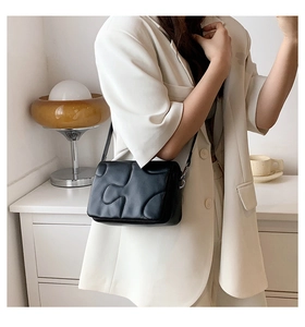 Close-up of a black quilted puffer shoulder bag with a unique bubble texture design