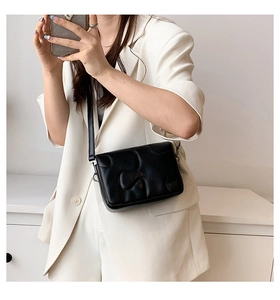Detail of black quilted leather crossbody bag featuring 3D cloud-like relief texture