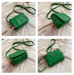 Detail view of grass green small square bag with puzzle stitching and adjustable strap