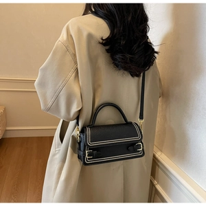 Detailed back view of model wearing a black litchi pattern bag with gold rivet accents