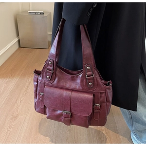 Detail of vintage burgundy leather tote bag with metallic buckle and soft oily texture