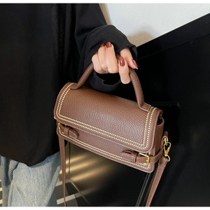 Detailed close-up of brown litchi pattern leather bag with gold studs and hardware
