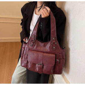 Vintage burgundy tote bag with leather buckle detail shown on shoulder for daily commute