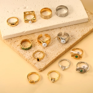 Mix of gold and silver plated rings with pearls and emeralds on marble stones