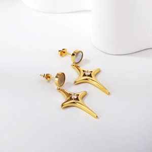 Élégantes boucles d'oreilles étoile dorées avec nacre et zircons sur fond blanc