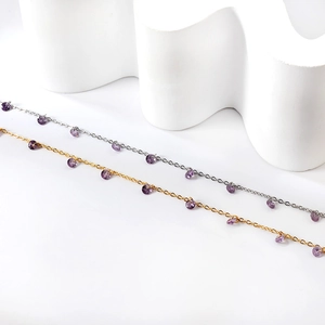 Bracelets de cheville en or et argent avec des breloques en cristal violet sur fond blanc