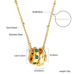 Détail macro du collier en acier inoxydable doré avec pierres vertes et maille à billes