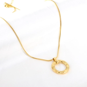 Détail d'une chaîne serpent dorée avec pendentif rond texturé et fermoir homard