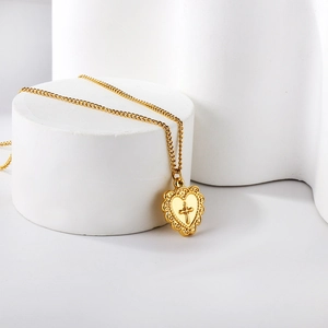 Vue détaillée du pendentif cœur doré avec gravure de croix et bords évidés complexes