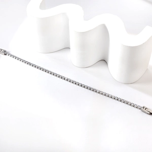 Elegantes Tennisarmband aus Edelstahl mit weißen Zirkonia-Steinen auf weißem Steinhintergrund