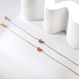 Detailansicht von Gold- und Silberarmbändern mit roten und lila Emaille-Schmetterlingen