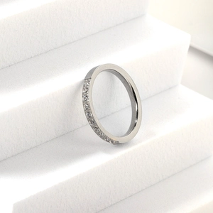 Minimalist stainless steel ring with micro-pave diamonds on a white tiered stand