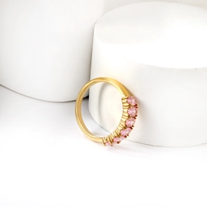 Elegant gold ring featuring six oval pink gemstones on minimalist white geometric pedestals