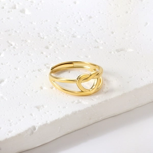 Minimalistischer doppellagiger Goldring mit Knoten und Herz auf weißem Naturstein