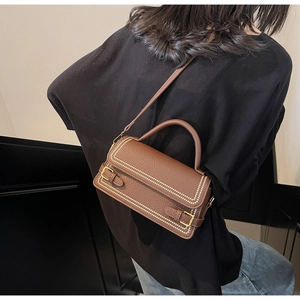 Close-up of brown litchi pattern handbag showing detailed white stitching and metal buckle