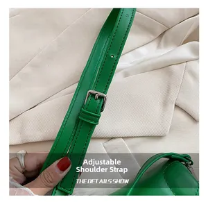 Close-up of adjustable shoulder strap with silver buckle on green leather crossbody bag