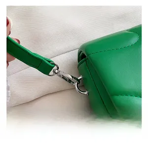 Detail of green quilted leather handbag featuring silver metal spring hook and D-ring