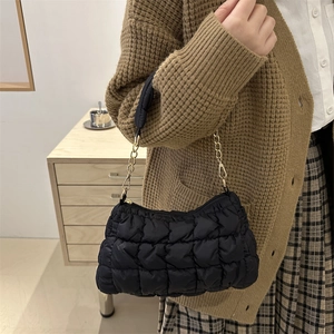 Chic black quilted puff cloud shoulder bag with gold chain strap in cozy autumn scene