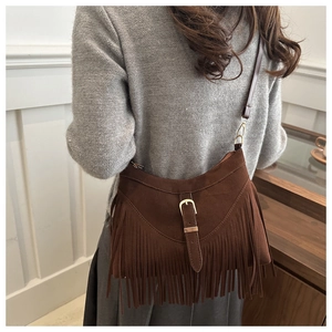 Close-up of deep brown suede fringe bag with bohemian tassels and metal buckle detail