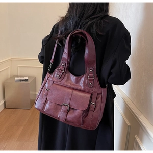 Close-up of wine red faux leather tote bag carried by a model in a minimal setting