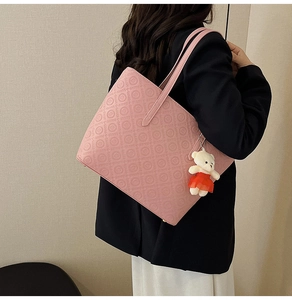 Pink tote bag detail with letter embossing and cute bear charm worn by a model