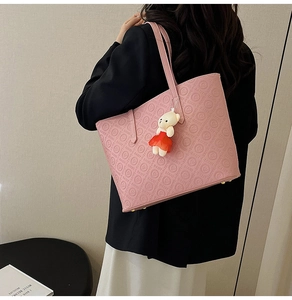 Detail shot of pink embossed tote bag with letter patterns and cute plush bear charm
