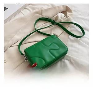 Detail view of green puzzle-patterned crossbody bag with silver-tone hardware accents
