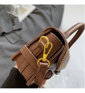 Detailed close-up of premium brown litchi leather bag with polished gold metal lobster clasp