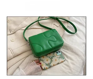 Detailed size comparison of the green crossbody bag next to a smartphone