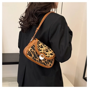 Close-up of leopard print underarm bag with brown leather trim on a model in a black suit