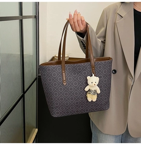 Deep grey monogram tote bag with brown straps and cute bear charm shown in use