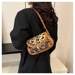 Detailed view of leopard print canvas shoulder bag with brown leather trim on model