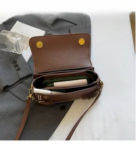 Detail view of brown leather crossbody bag interior showing magnetic snaps and large capacity